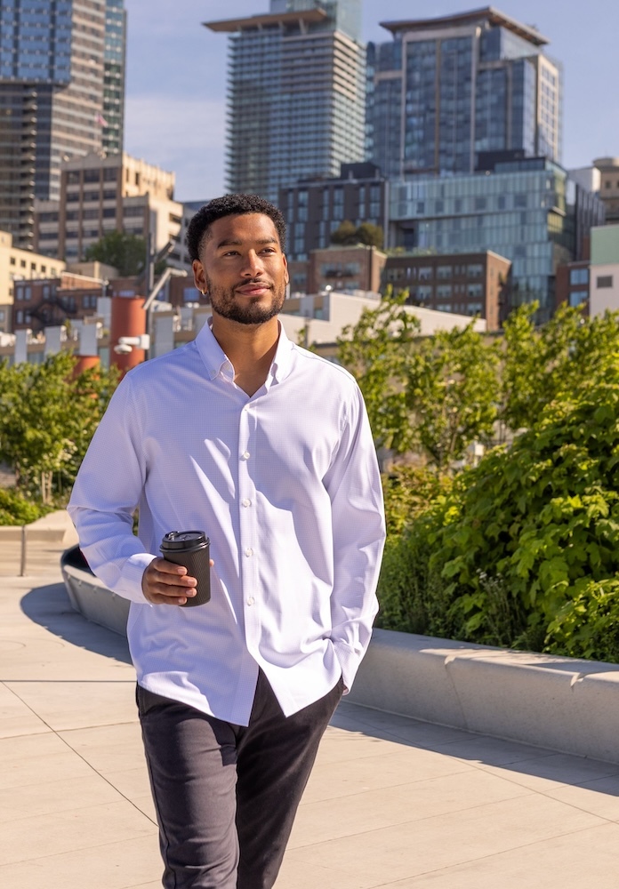 Man wearing Cutter & Buck Skyline Windowpane dress shirt while walking through the city with coffee in hand